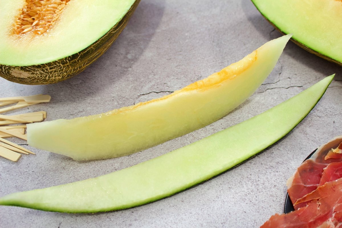 Cortando la piel de la rodaja del melón para seguir haciendo el melón con jamón