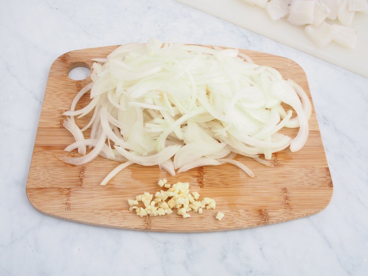 Cortar el ajo y la cebolla para la sepia encebollada