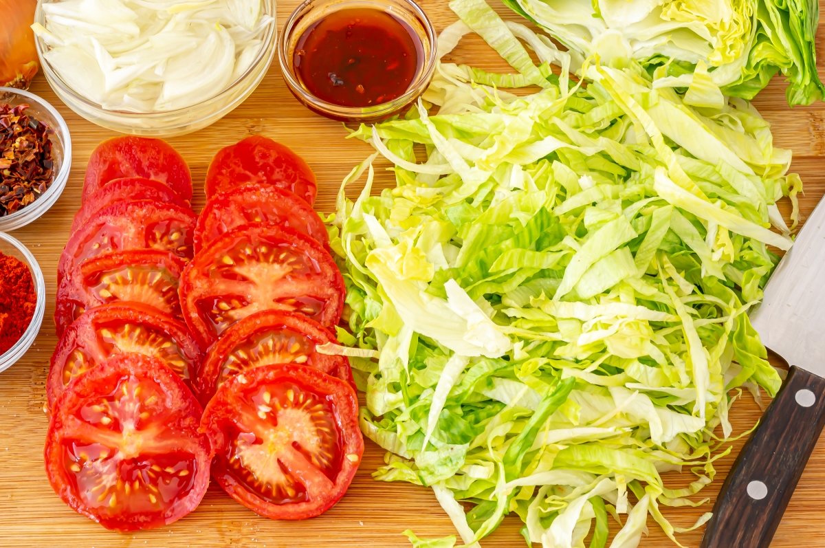 Cortar el tomate, lechuga y cebolla para el sándwich de milanesa