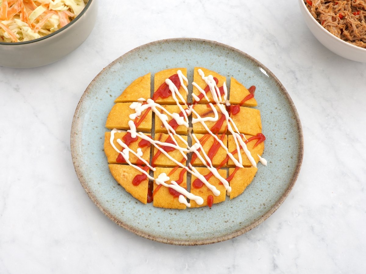 Cortar la arepa y añadir mayonesa y kétchup