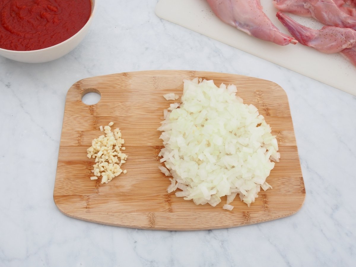 Cortar la cebolla y el ajo para el conejo con tomate