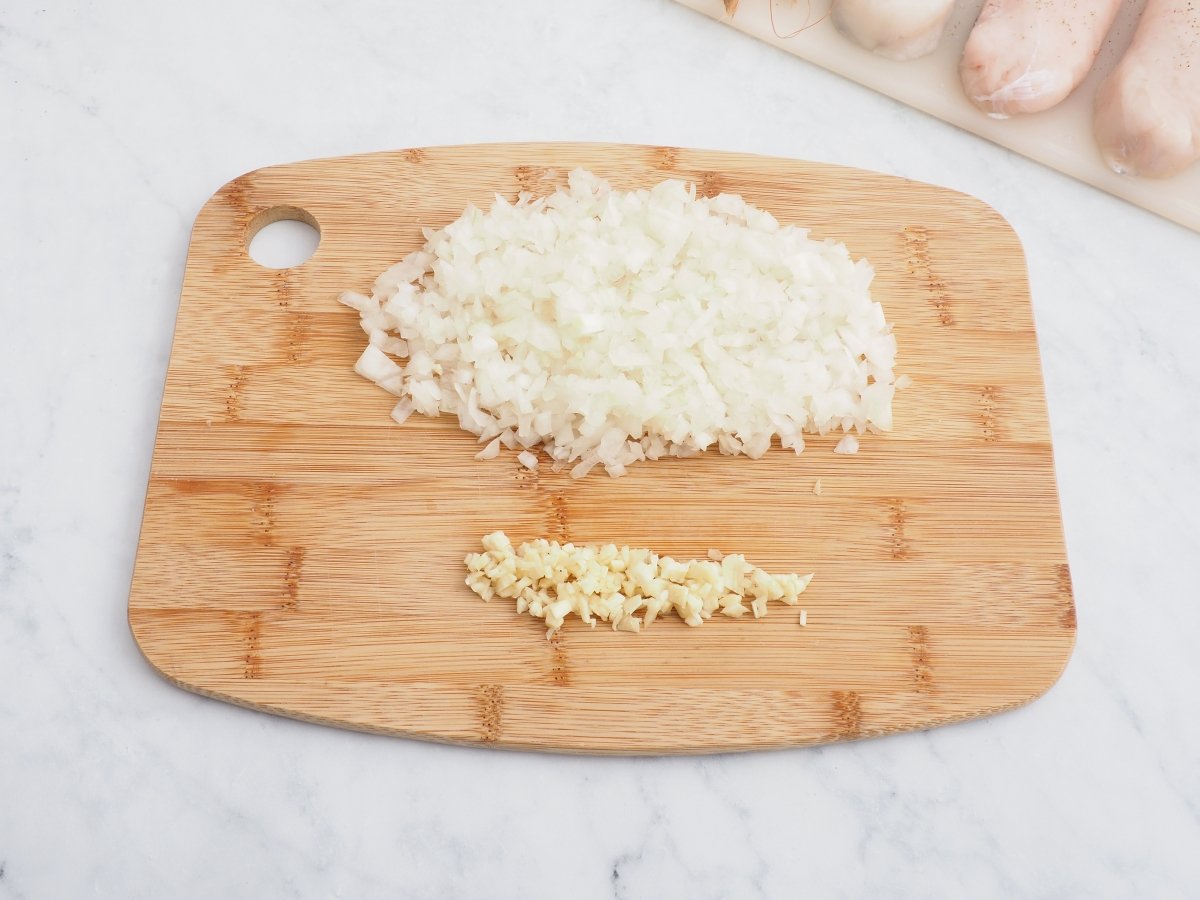 Cortar la cebolla y el ajo para la merluza con gambas