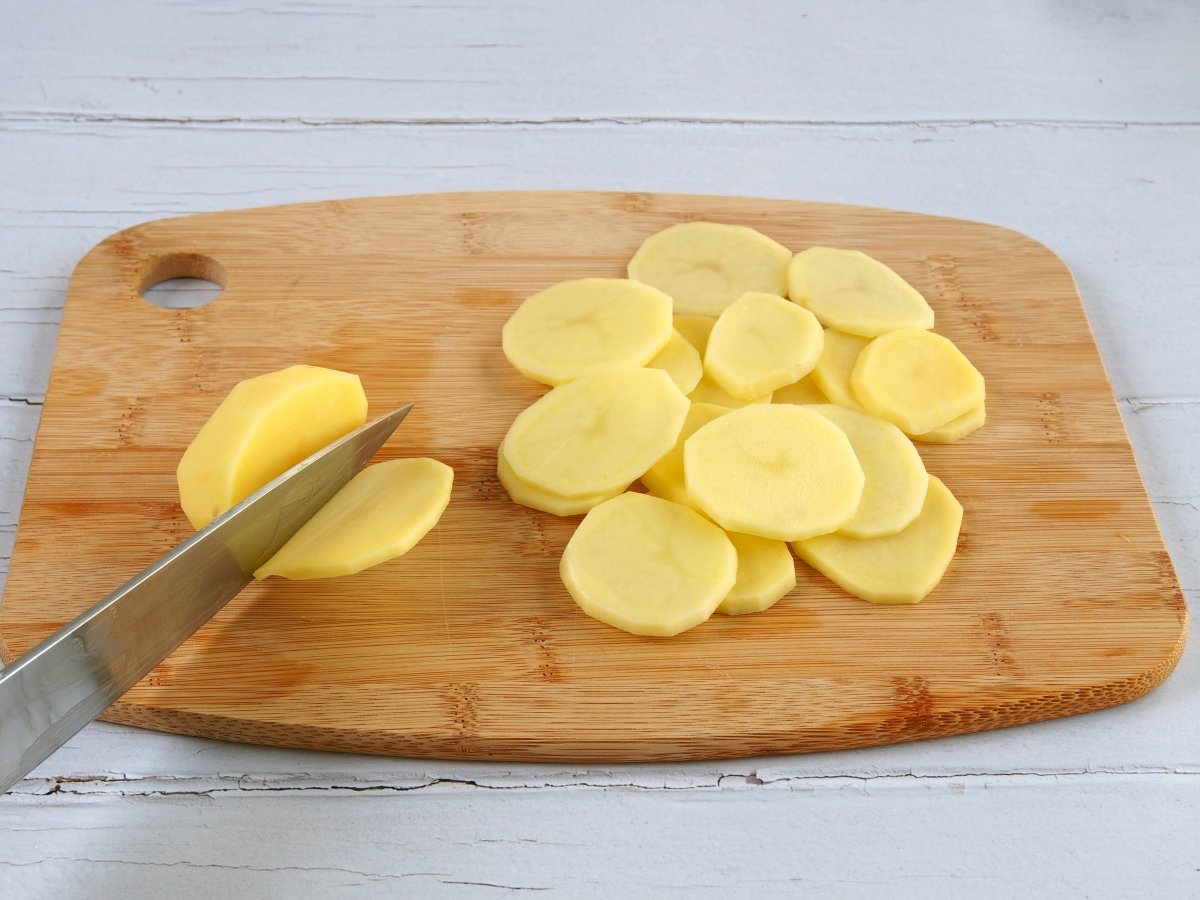 Cortar las patatas en rodajas para los huevos rotos con jamón