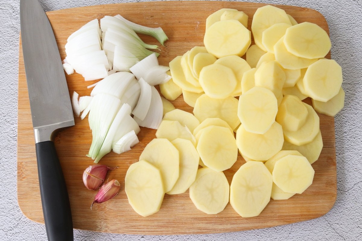 Cortar las patatas, la cebolla y los ajos para el atún al horno