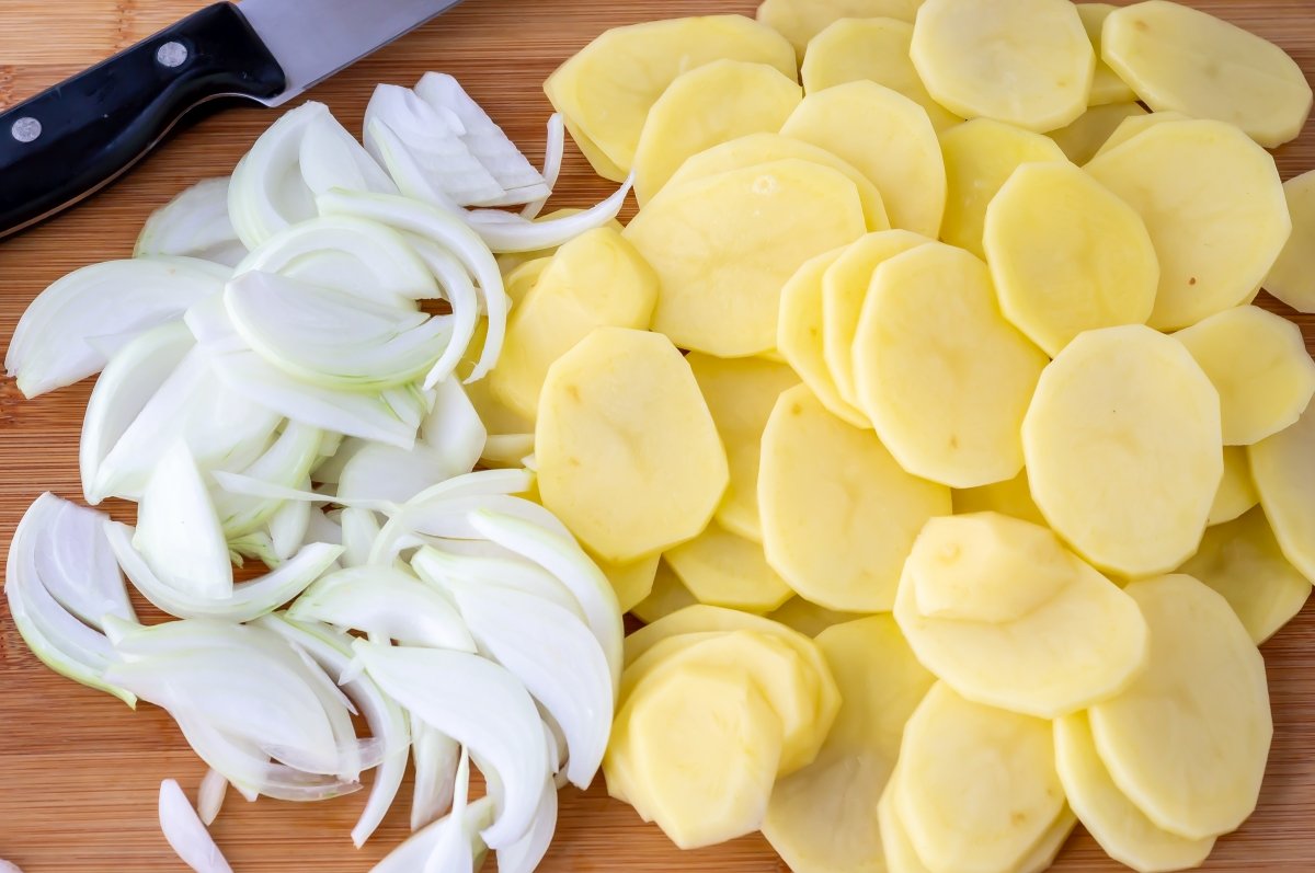 Cortar las patatas y cebolla para el fletán al horno