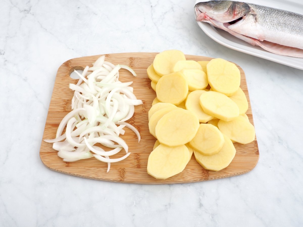 Cortar las patatas y cebolla para la lubina a la espalda