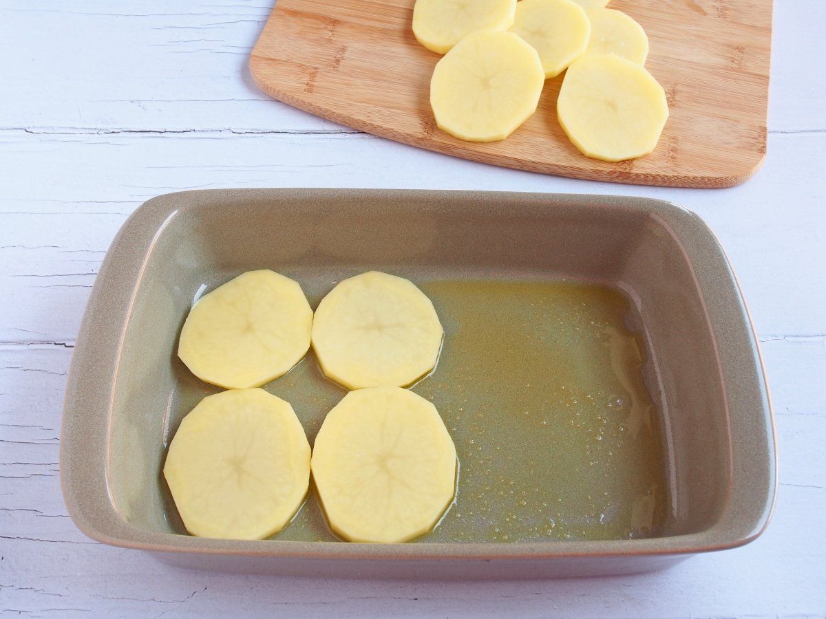 Cortar las patatas y colocarlas en una fuente de horno con aceite de oliva y sal en la base