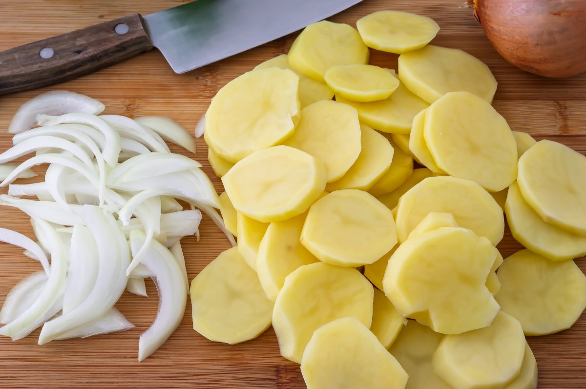 Cortar las patatas y la cebolla para la lubina rellena
