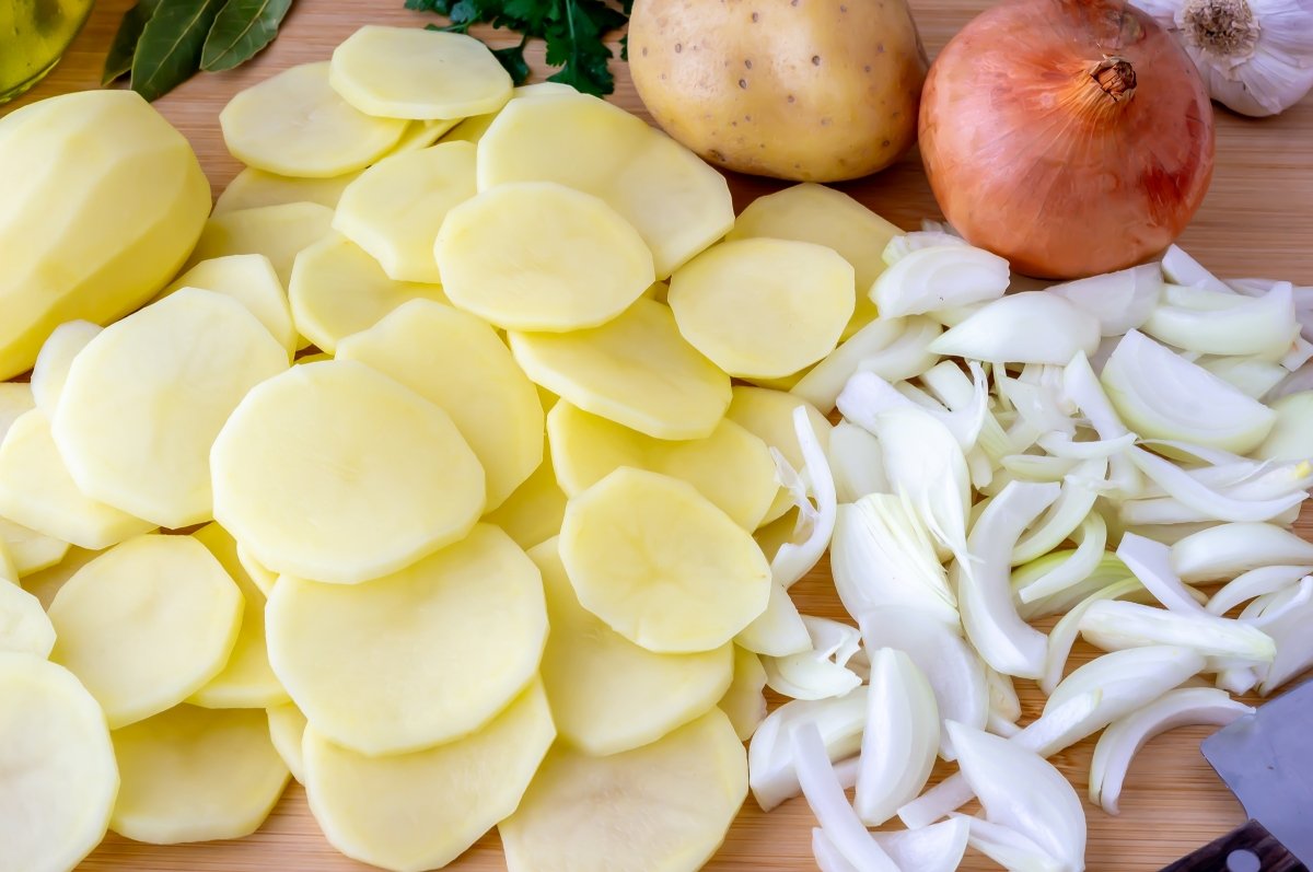 Cortar las patatas y la cebolla para la merluza al horno