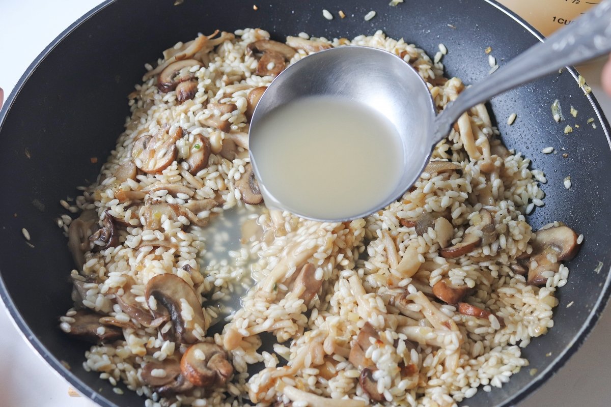 Cuando el arroz esté bien caliente incorporar un par de cazos de caldo y volver a añadir la cebolla