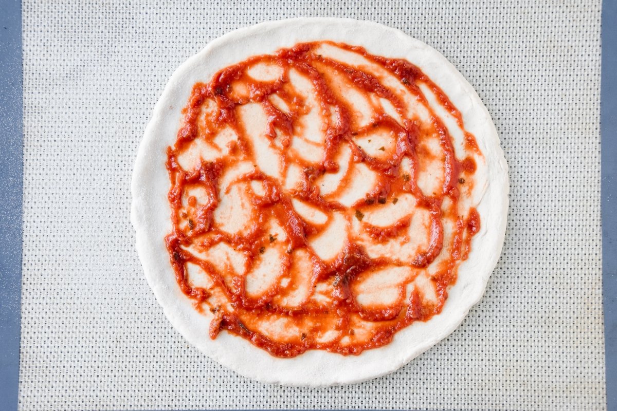 Cubrimos la masa de pizza con la salsa de tomate