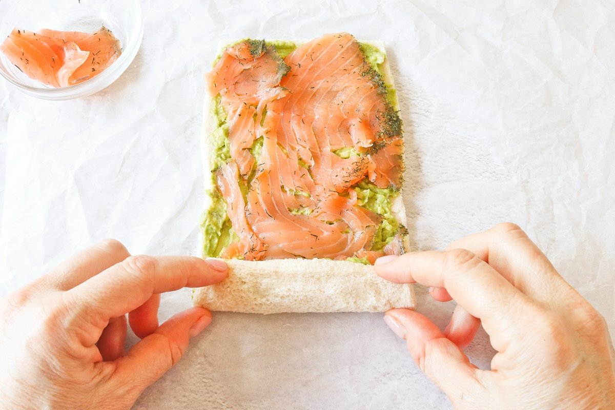 Cubrir con salmon y enrollar el rollo de pan de molde