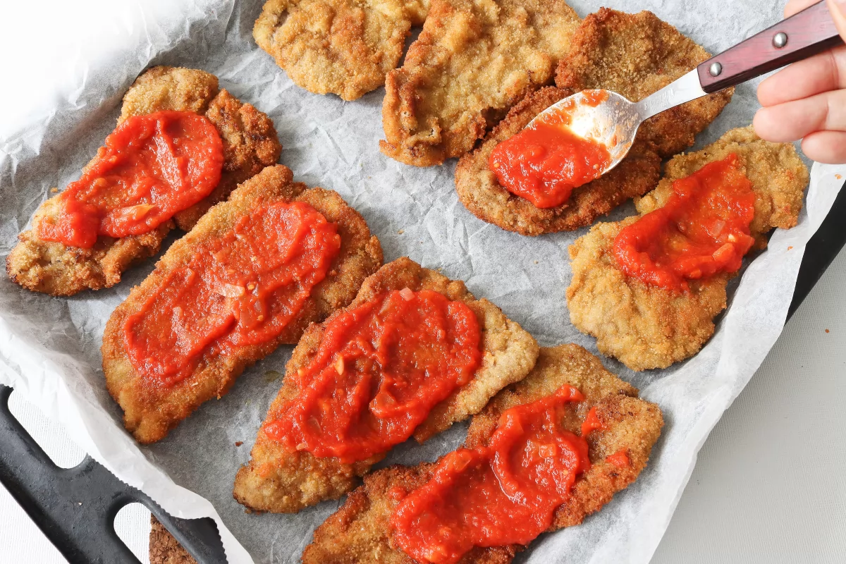 Milanesa a la napolitana 6 Cubrir con salsa de tomate casera la milanesa a la napolitana