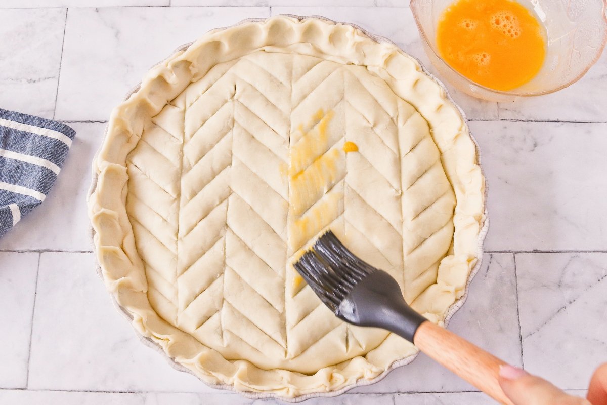 Cubrir el pastel de pollo con hojaldre y pintarlo con huevo