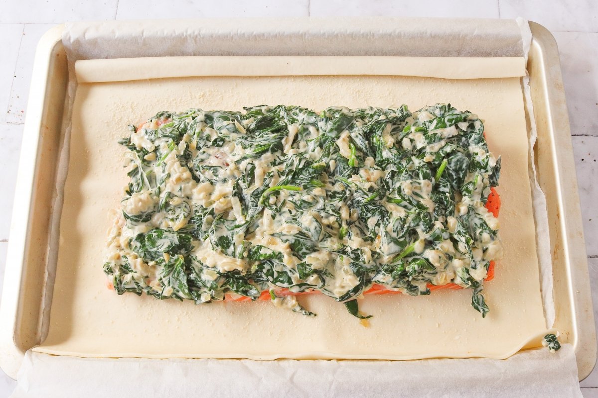 Cubrir el salmón con las espinacas para el salmón Wellington