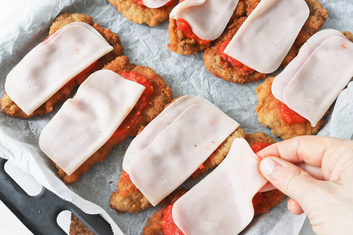Milanesa a la napolitana 8 Cubrir la salsa de tomate con jamón dulce para la milanesa a la napolitana