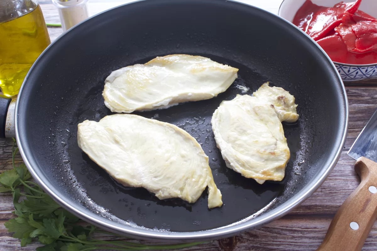 Dando la vuelta a los filetes de la pechuga de pollo a la plancha