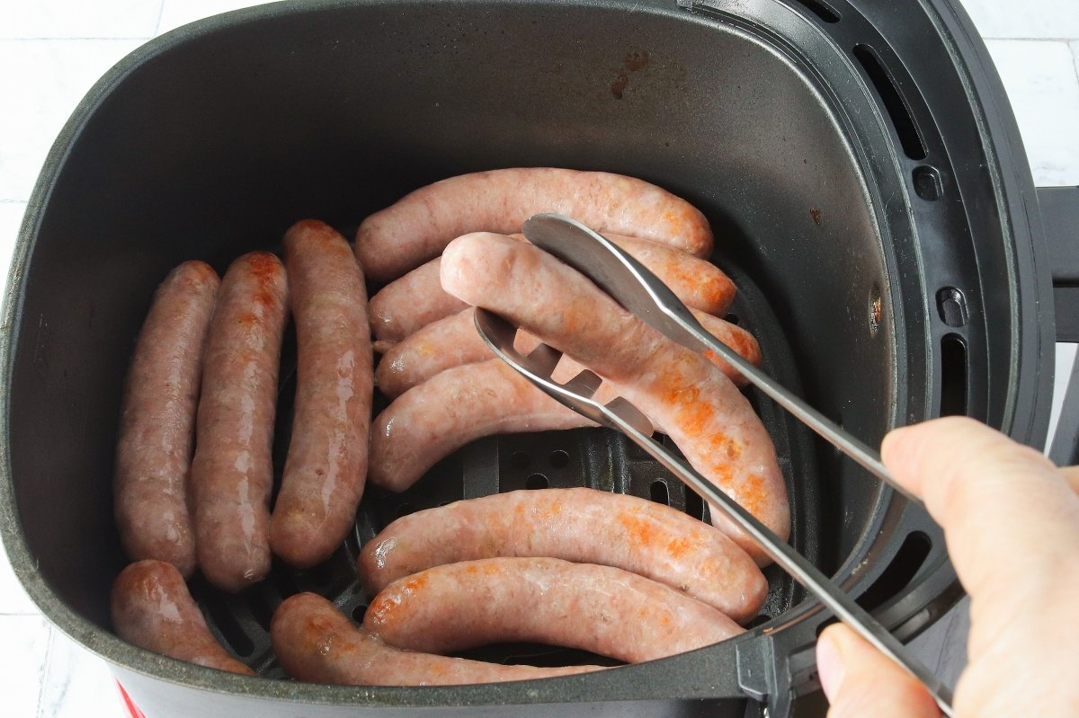 Dar la vuelta a las salchichas cocinadas en freidora de aire