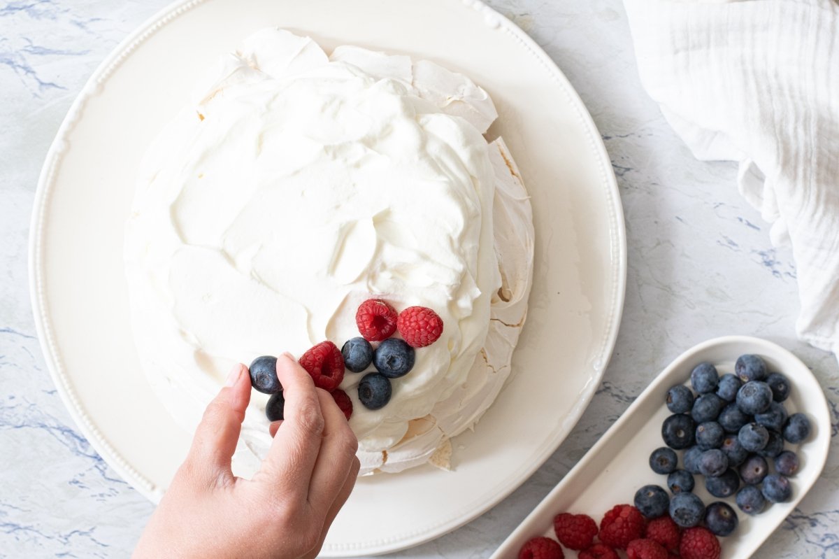 Decoramos al gusto con los frutos rojos la tarta Pavlova