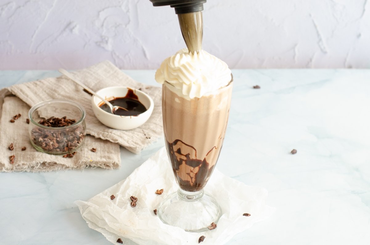 Decorando el milkshake de chocolate con nata montada
