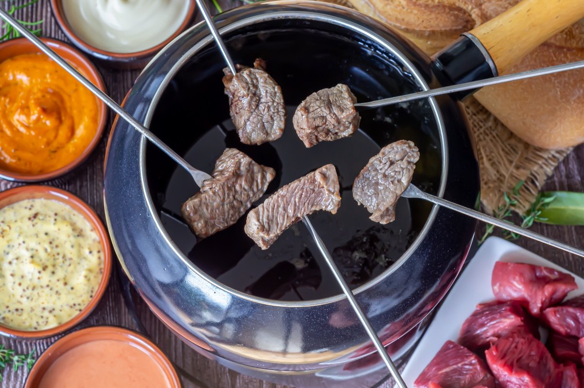 Degustar la carne frita en la fondue con salsas