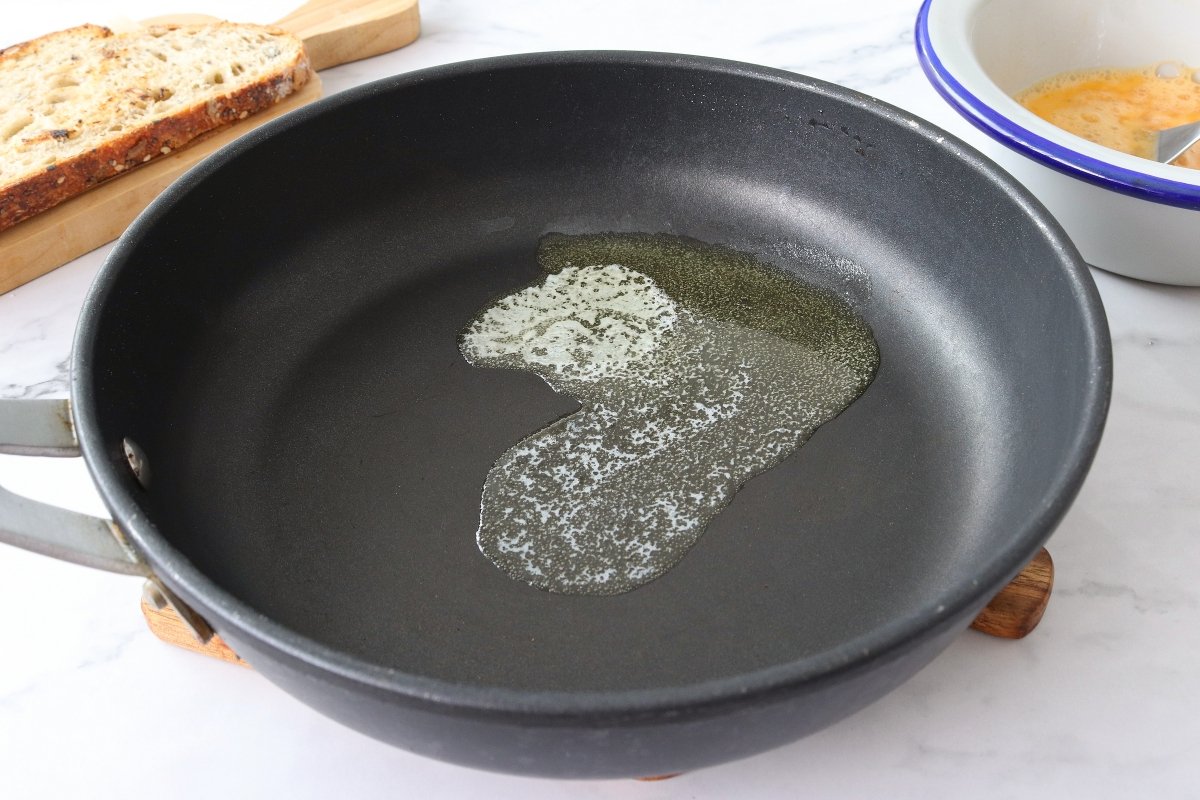 Derretir la mantequilla para la tostada de huevos revueltos con jamón