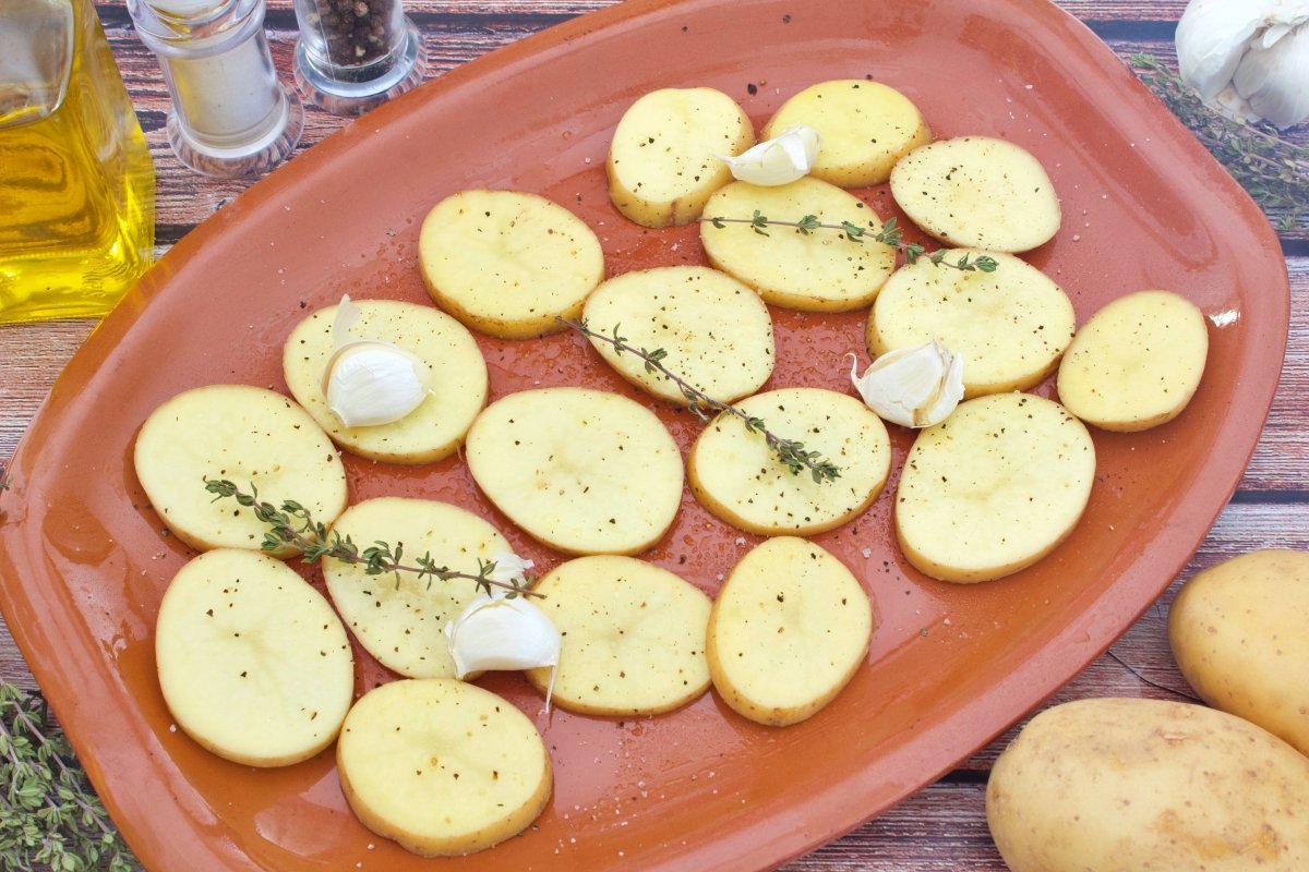 Dientes de ajo y tomillo sobre las patatas del cabrito al horno con patatas