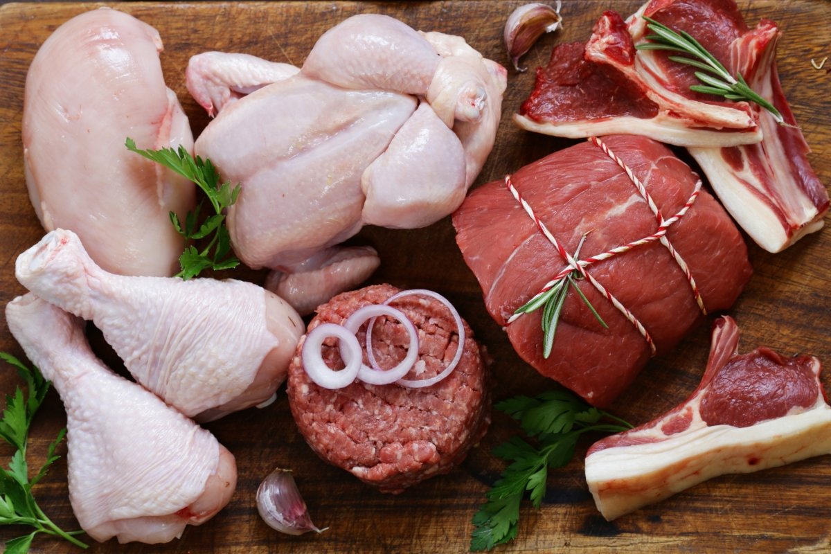 Diferentes tipos de carne (hamburguesas, un pollo entero, pechuga, muslitos...) sobre madera