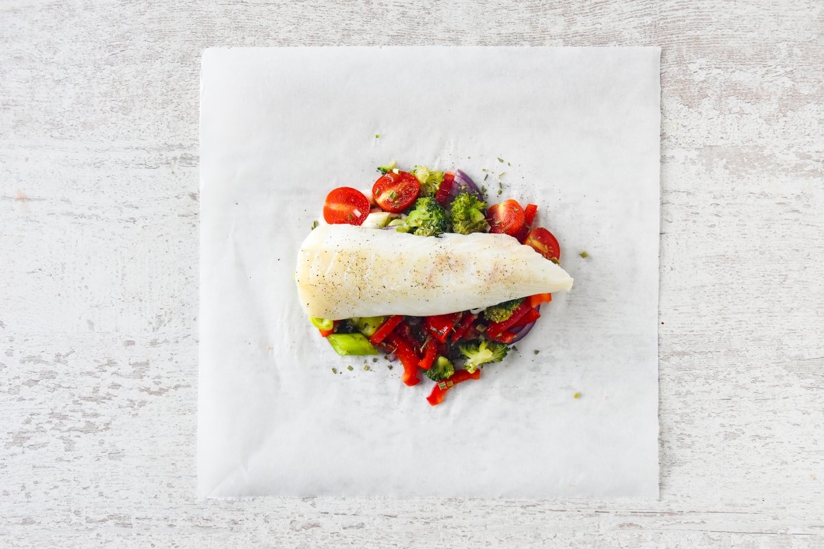 Disponemos las verduras y el bacalao sobre el papel vegetal