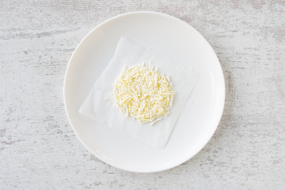 Disponemos un círculo de queso rallado en un plato sobre papel de horno