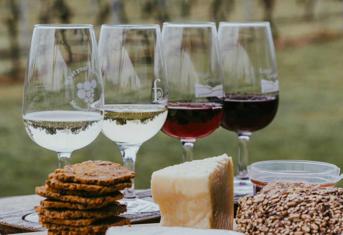Distintas copas de vino tinto y blanco junto a quesos y snacks