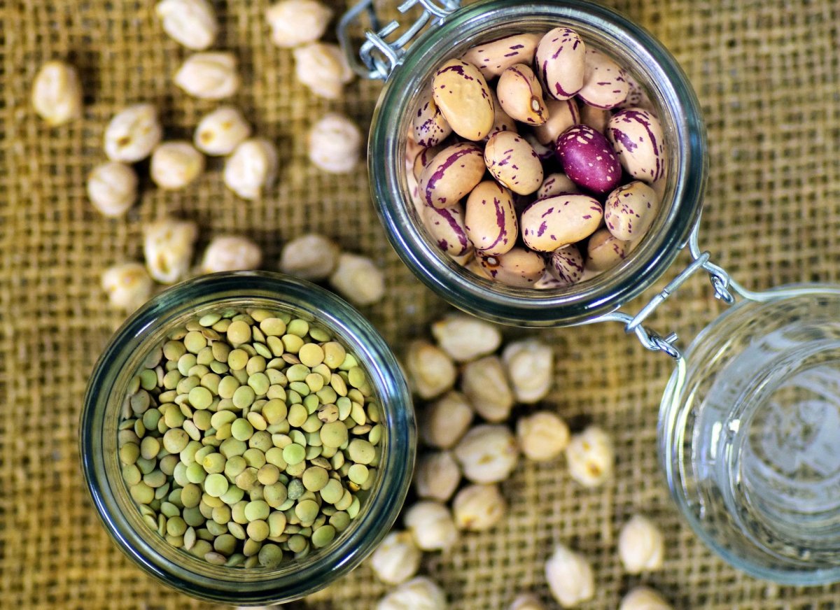 Two glass containers with raw lentils and broad beans