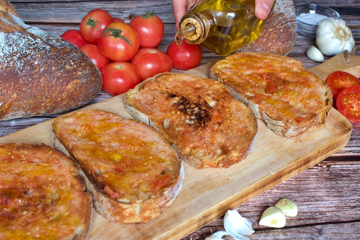 Echando aceite sobre el pan del pan con tomate (pa amb tomàquet)