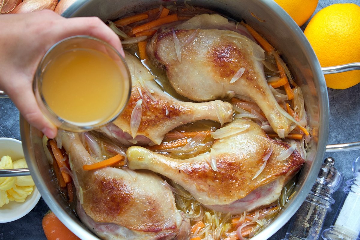 Echando el caldo de carne en la olla del pato a la naranja