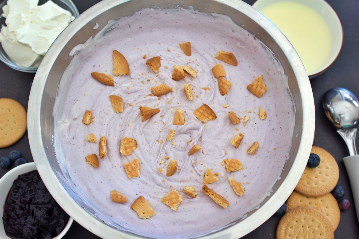 Echando trozos de galletas María para seguir haciendo el helado de cheesecake