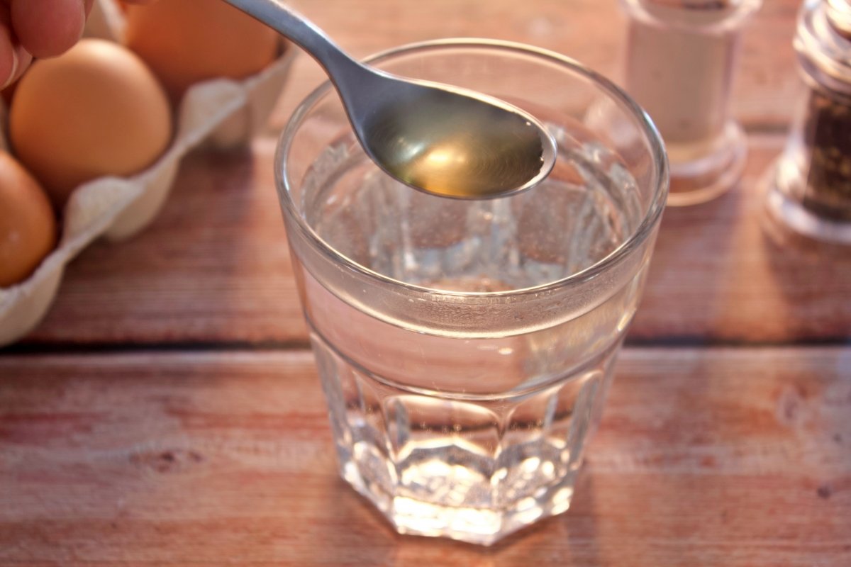 Echando vinagre en un vaso de agua para hacer huevo poché al microondas