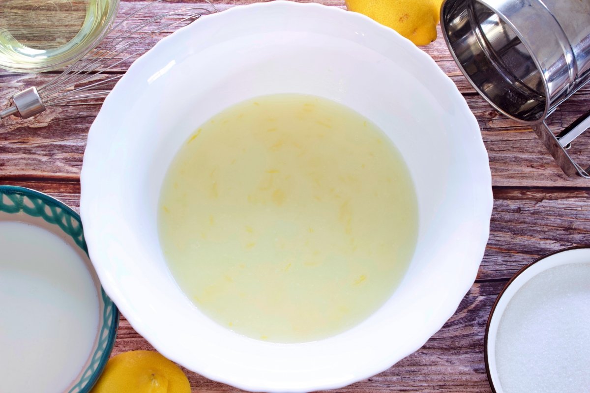 El azúcar, el aceite, la leche y la ralladura de limón de las magdalenas sin huevo mezclados en un b