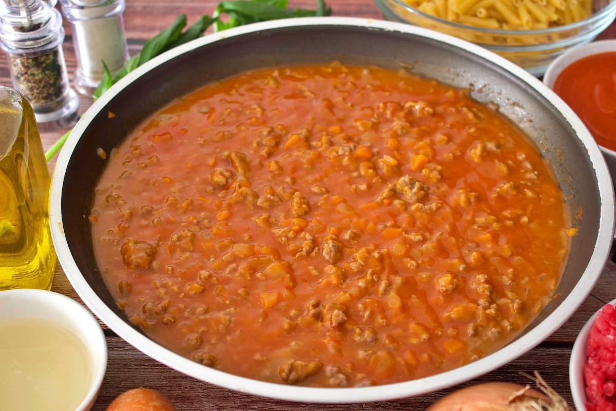 El tomate frito de los macarrones a la boloñesa con carne picada añadido a la sartén