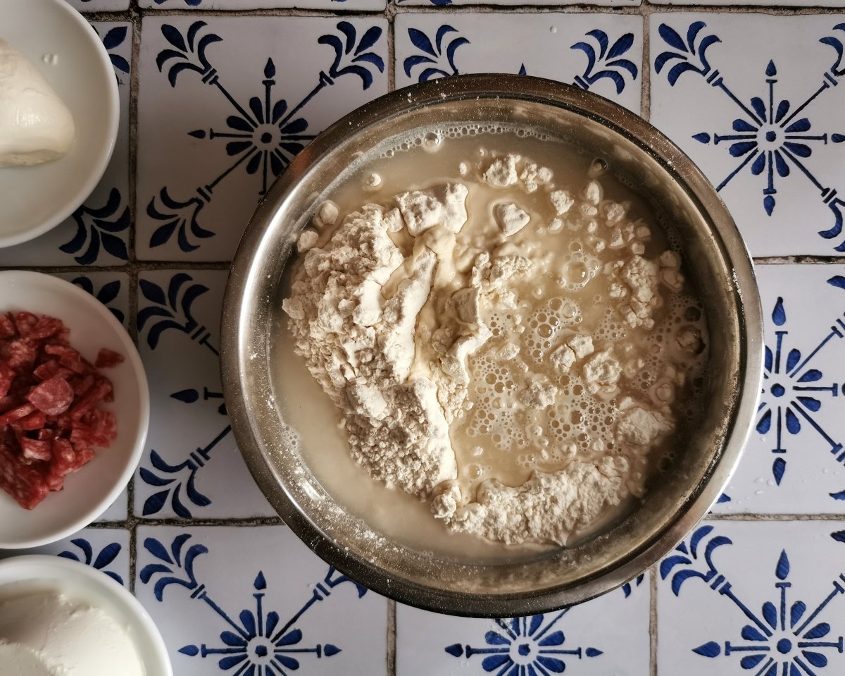 En un bol poner la harina, la levadura desmigada con los dedos y el agua.
