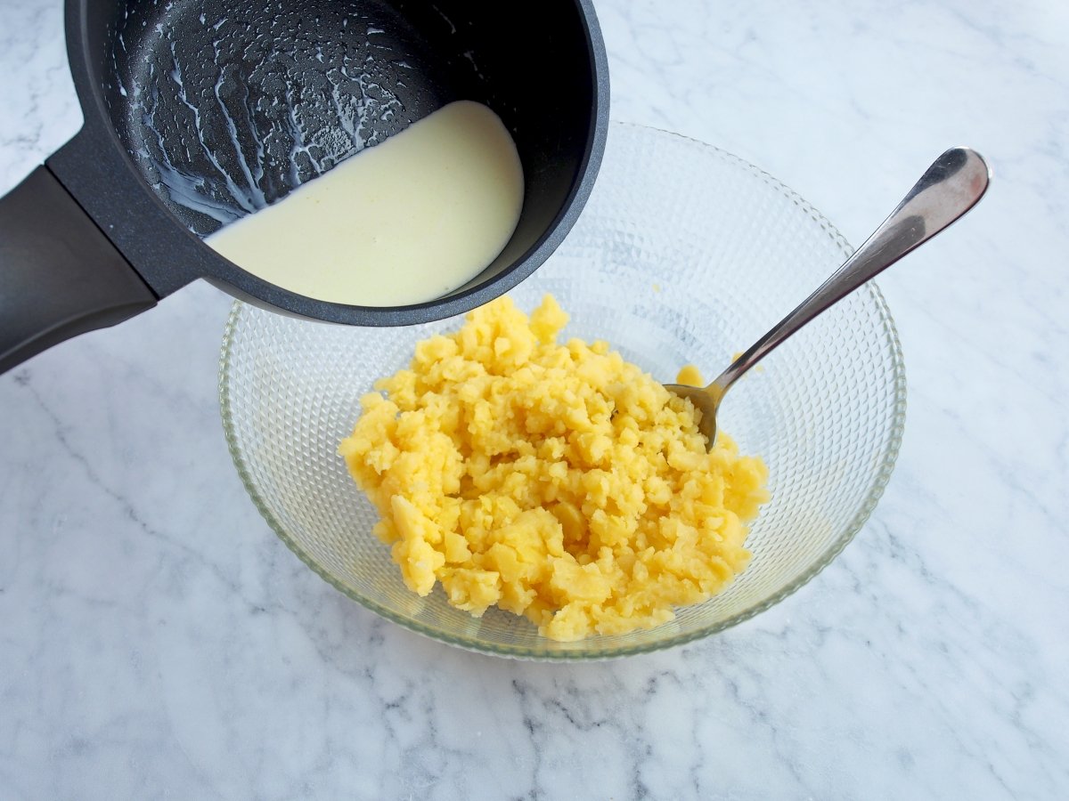 En un cazo, calentar mantequilla y nata e incorporar esta mezcla a las patatas