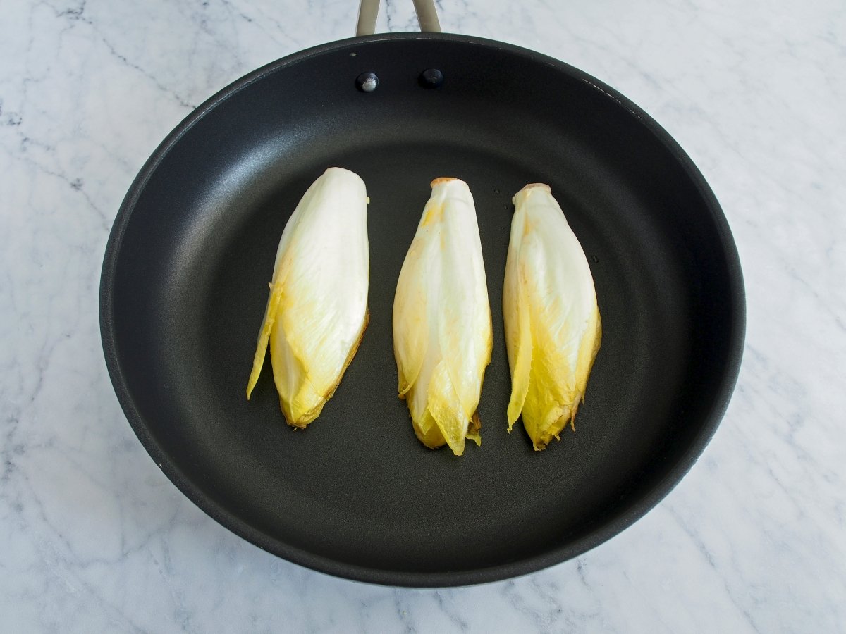 In a skillet over high heat, place the endives with the inside part down