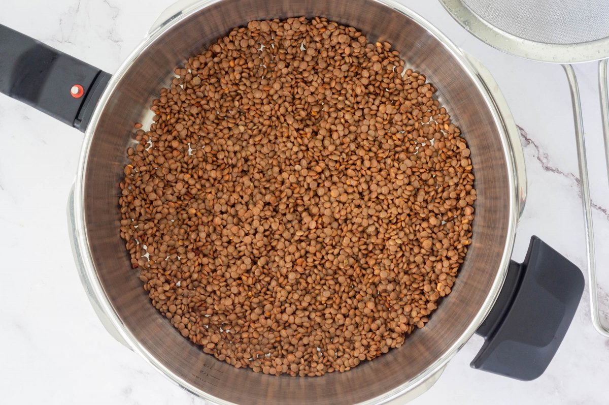 Enjuagar las lentejas y ponerlas en la olla exprés