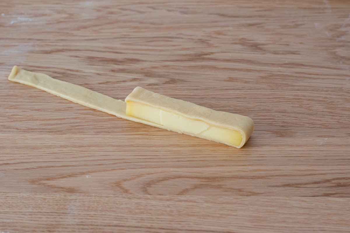 Roll the dough of the cheese tequeños all over the cheese strip