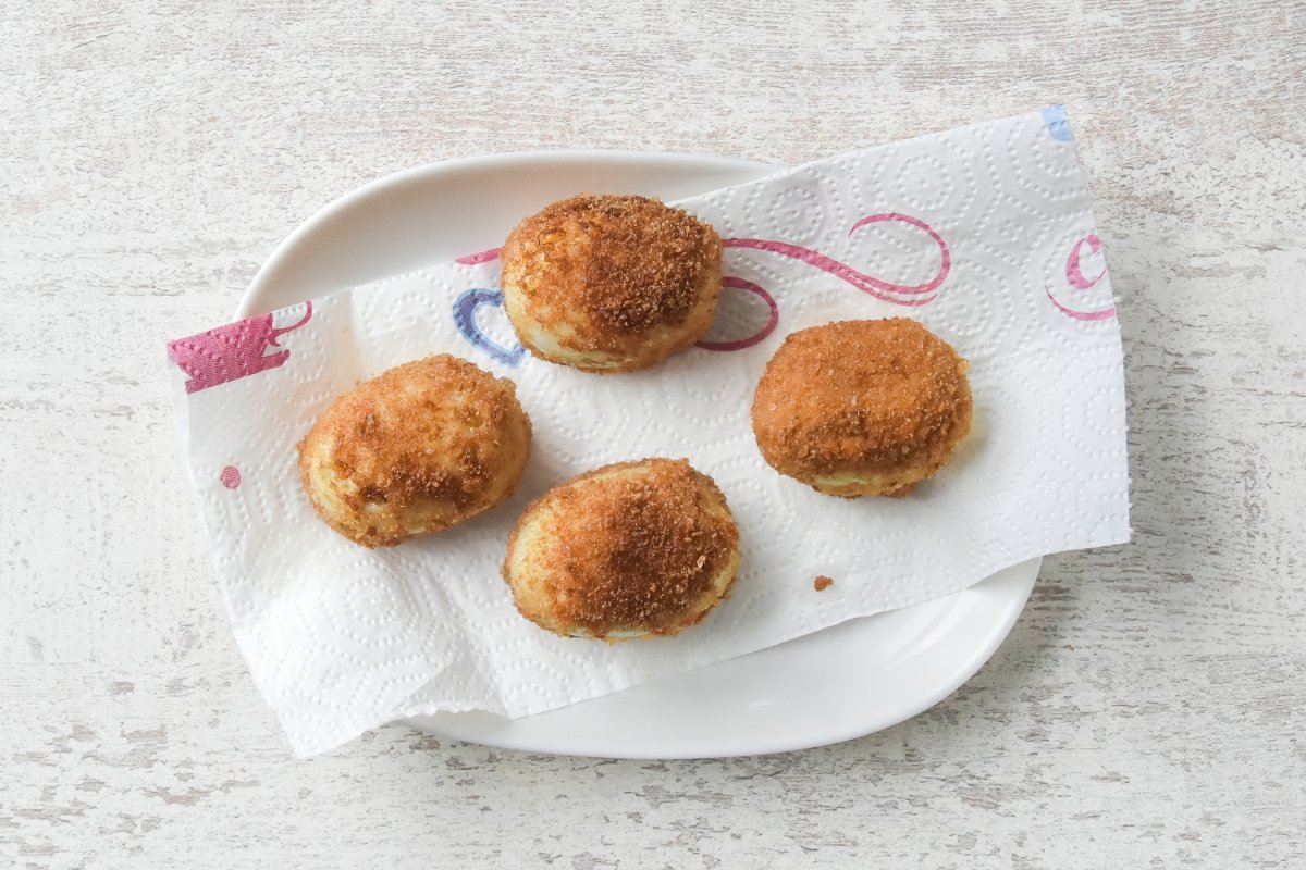 Escurrimos los huevos rellenos rebozados sobre papel de cocina