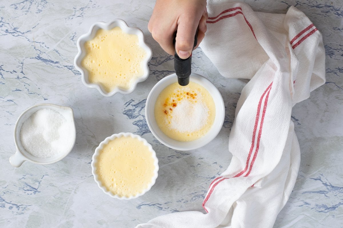 Espolvorear la crema catalana con azúcar