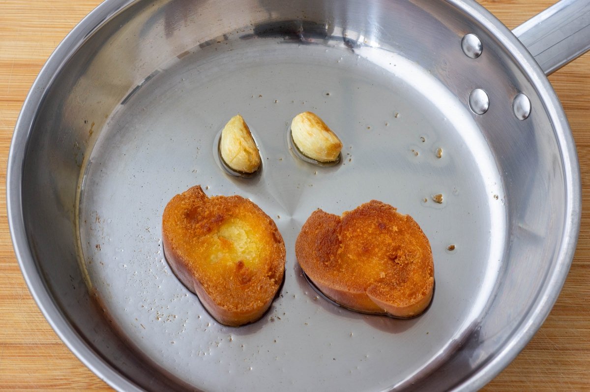 Freír el pan y dorar los ajos de las tagarninas esparragadas