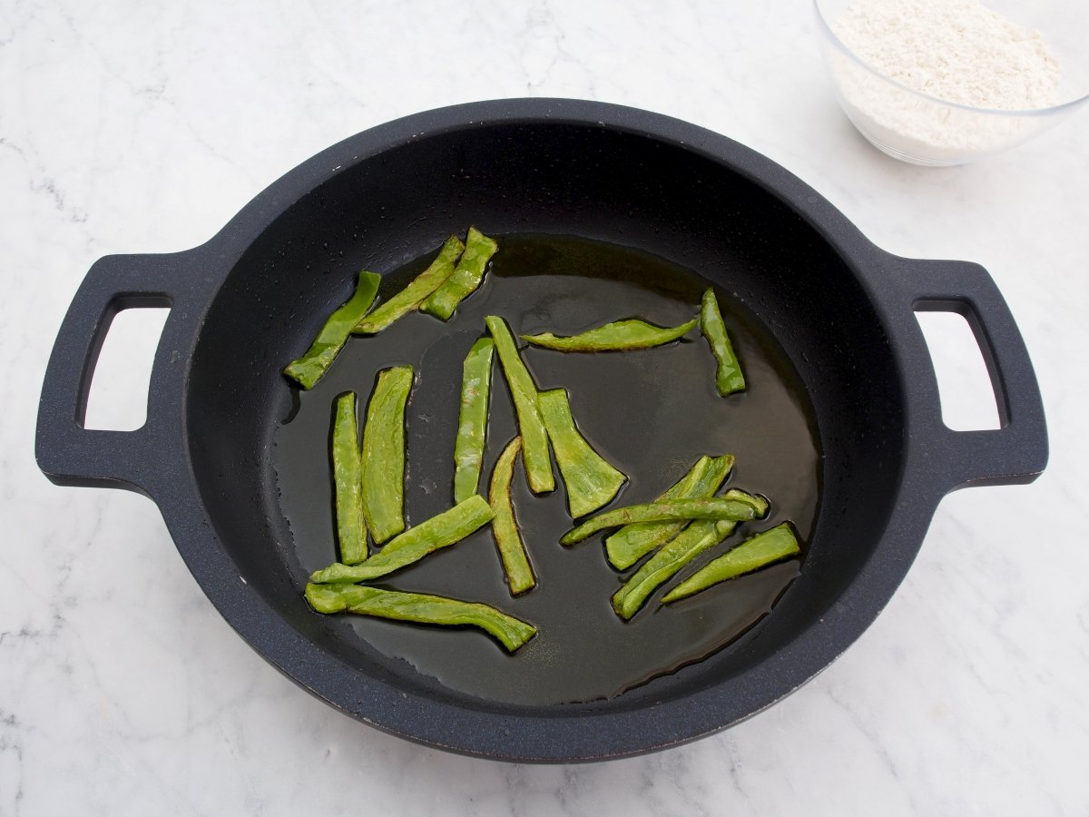 Freír el pimiento verde para las migas de harina