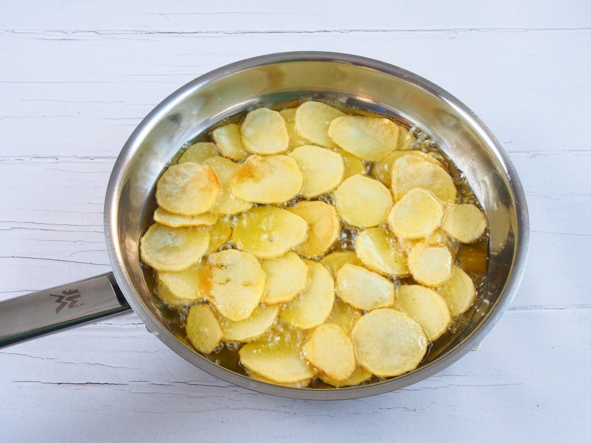 Freír las patatas para los huevos rotos con jamón