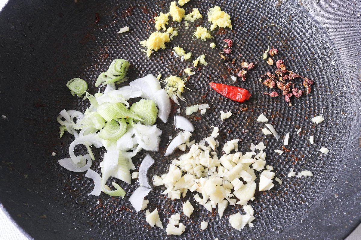 Freír las verduras y las especias para el pollo Kung Pao