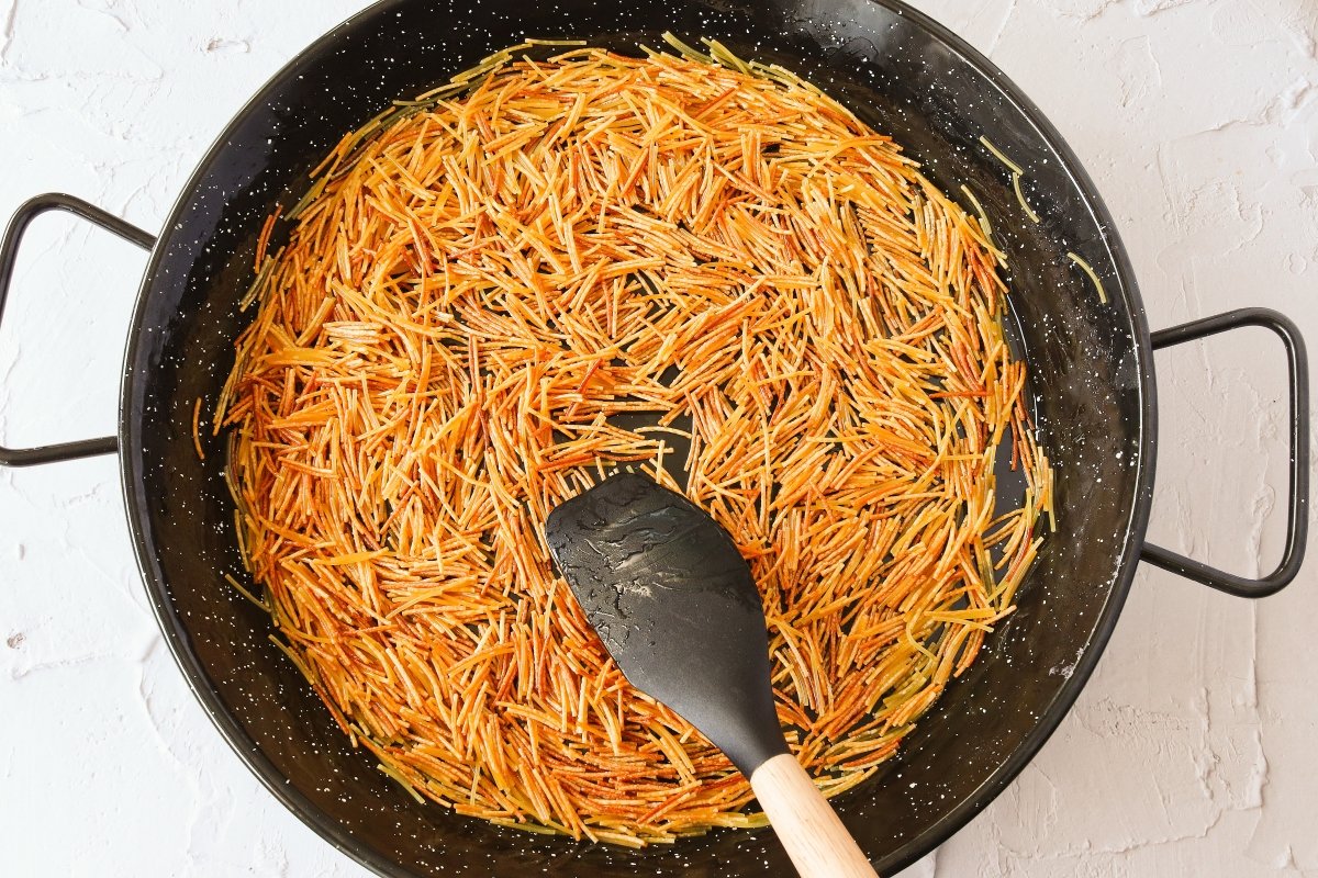 Freír los fideos para la fideuá con sepia